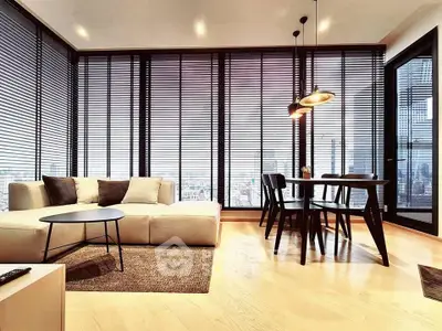 Modern living room with floor-to-ceiling windows and stylish dining area in a high-rise apartment.