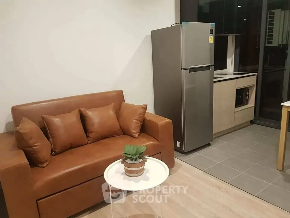 Modern apartment living room with brown sofa and sleek kitchen area.