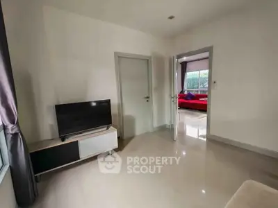 Modern living room with sleek TV stand and view into cozy bedroom.