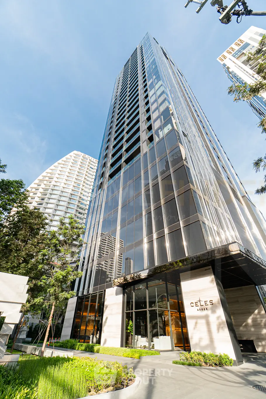 Stunning modern high-rise building with sleek glass facade and lush greenery, perfect for urban living.