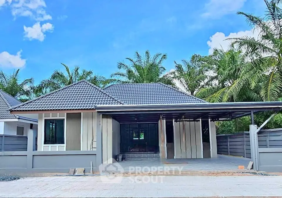Charming single-story house with modern design and spacious driveway, surrounded by lush greenery.
