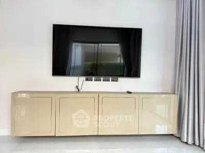 Modern living room with sleek TV setup and glossy cabinet
