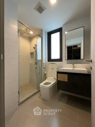 Modern bathroom with sleek design, featuring a glass shower and contemporary fixtures.