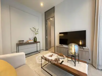 Modern living room with sleek furniture and stylish decor, featuring a flat-screen TV and elegant lighting.