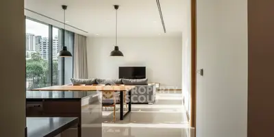 Modern living room with open kitchen, large windows, and stylish furniture in a high-rise apartment.