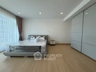 Spacious modern bedroom with large windows and sleek storage solutions.