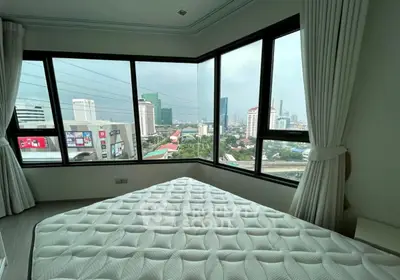 Spacious bedroom with panoramic city view and large windows in modern apartment.
