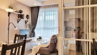 Modern living room with stylish decor and natural light, featuring cozy seating and elegant shelving.
