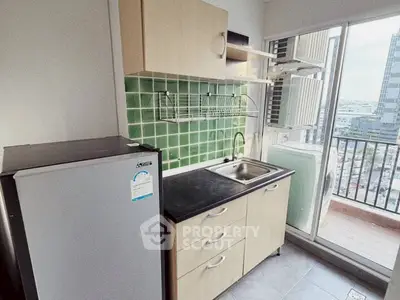 Compact kitchen with green tile backsplash and balcony view in modern apartment.