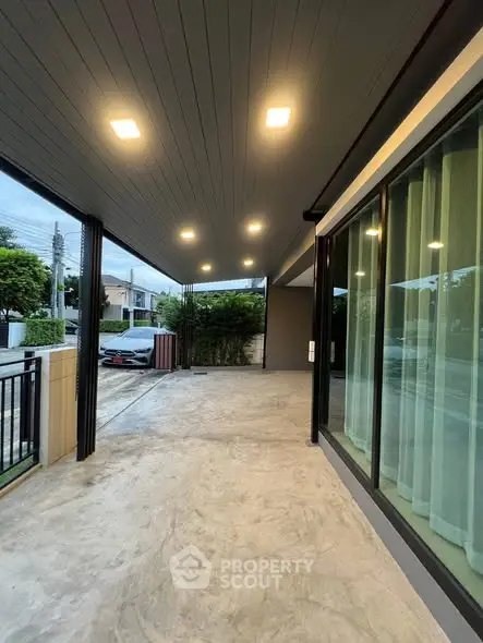 Modern covered parking area with sleek lighting and large windows in suburban home.