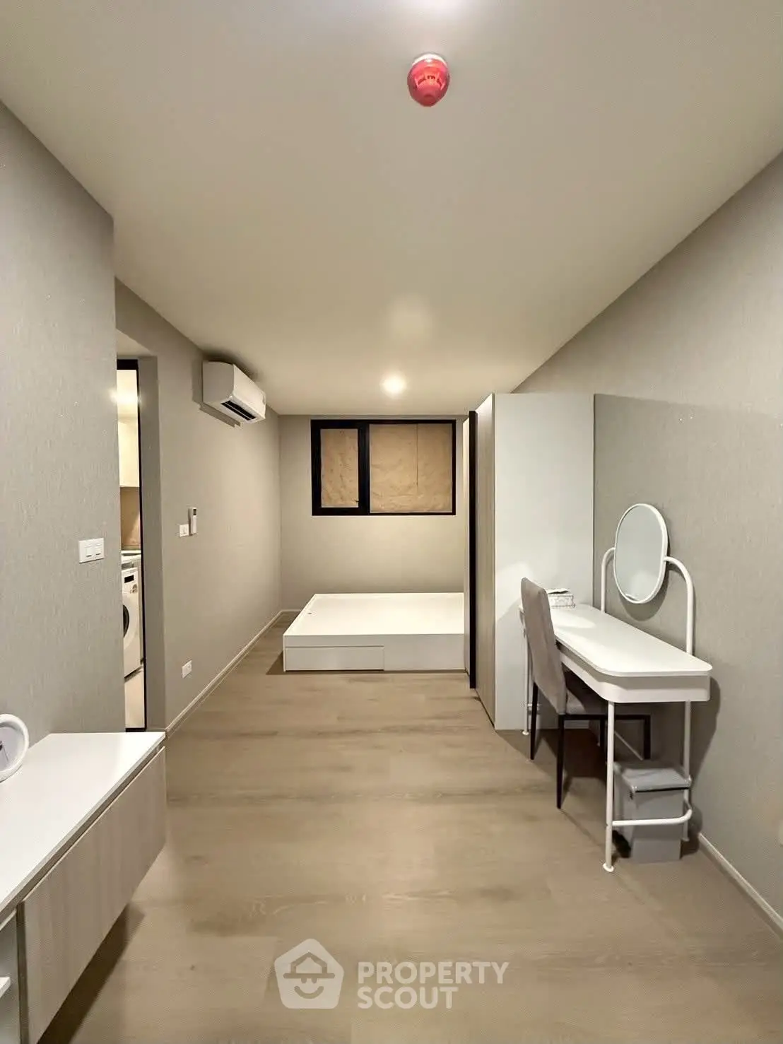 Modern bedroom with minimalist design, featuring a bed, vanity, and air conditioning in a sleek apartment.