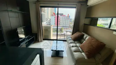 Modern living room with city view, cozy sofa, and sleek TV setup in urban apartment.