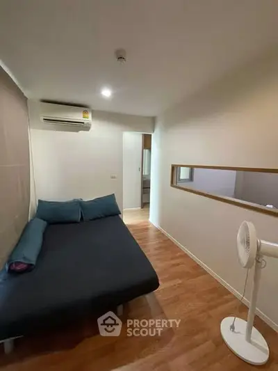 Cozy bedroom with wooden flooring and modern air conditioning unit, perfect for a comfortable living experience.