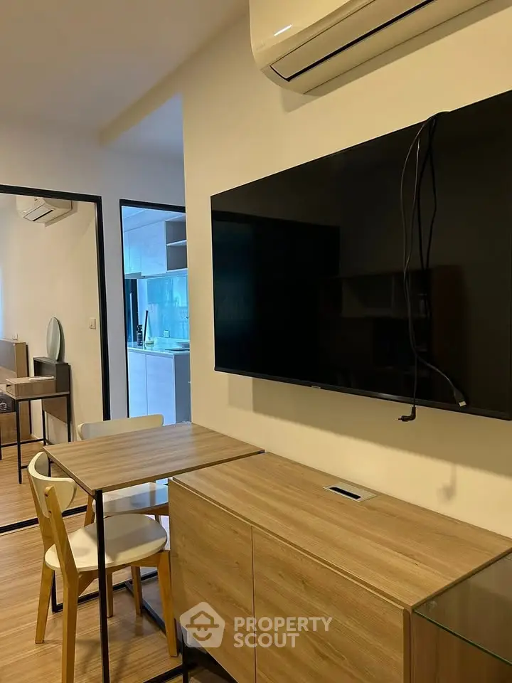 Modern living room with wall-mounted TV and dining area in stylish apartment