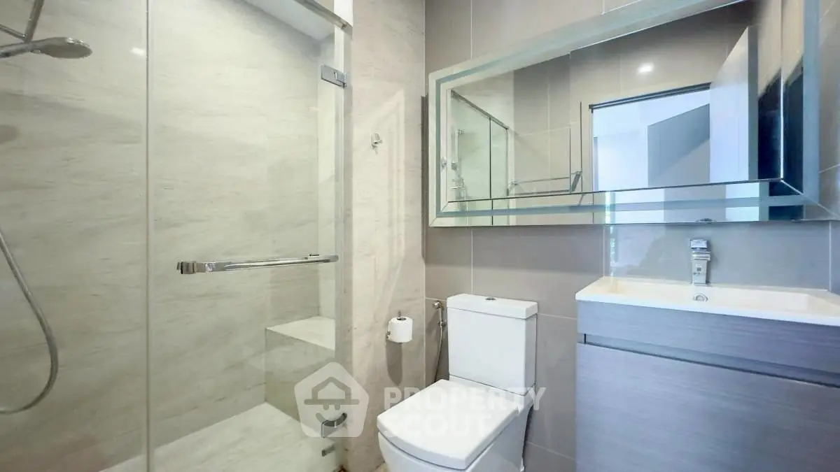 Modern bathroom with glass shower and sleek vanity in contemporary home.