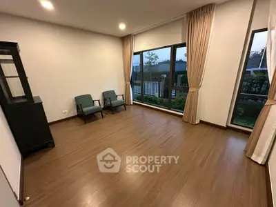 Spacious room with large windows and wooden flooring, ideal for versatile living space.