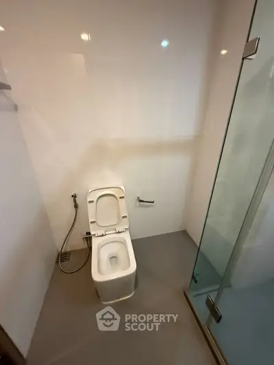 Modern bathroom with sleek design featuring a glass shower and white toilet.