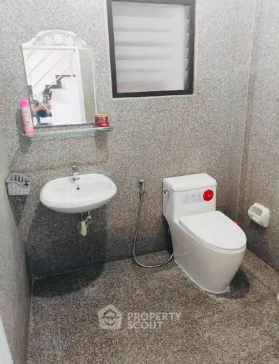 Modern bathroom with sleek fixtures and granite walls, featuring a stylish sink and toilet.