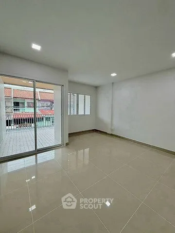 Spacious empty living room with glossy tiled floor and large windows leading to a balcony.