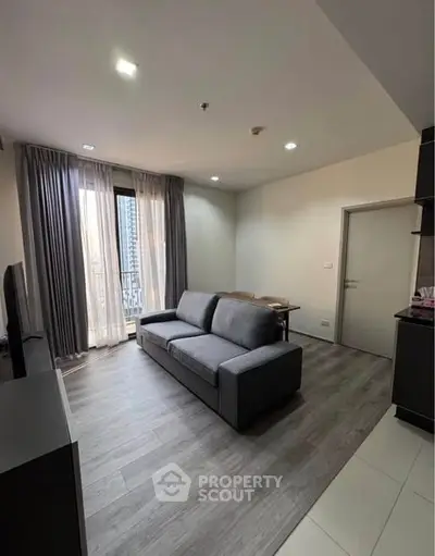 Modern living room with sleek gray sofa and large window, offering a cozy urban retreat.