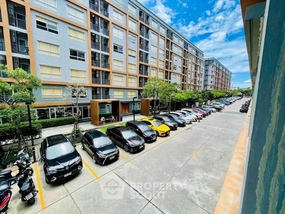 Modern apartment building with ample parking and lush greenery, perfect for urban living.