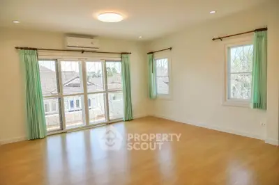 Spacious empty room with large windows and wooden flooring, perfect for customization.
