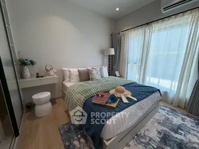 Cozy bedroom with stylish decor, large window, and natural light, perfect for relaxation and comfort.