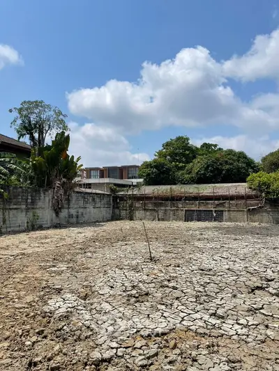 Vacant land with cracked soil under a clear blue sky, potential for development.