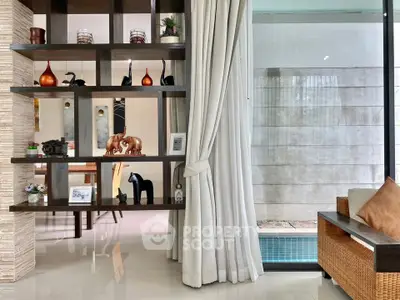 Elegant living room with modern decor and pool view, featuring stylish shelving and cozy seating.