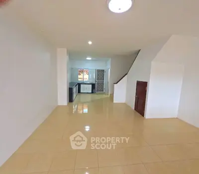 Spacious open-plan living area with tiled floors and modern kitchen setup.