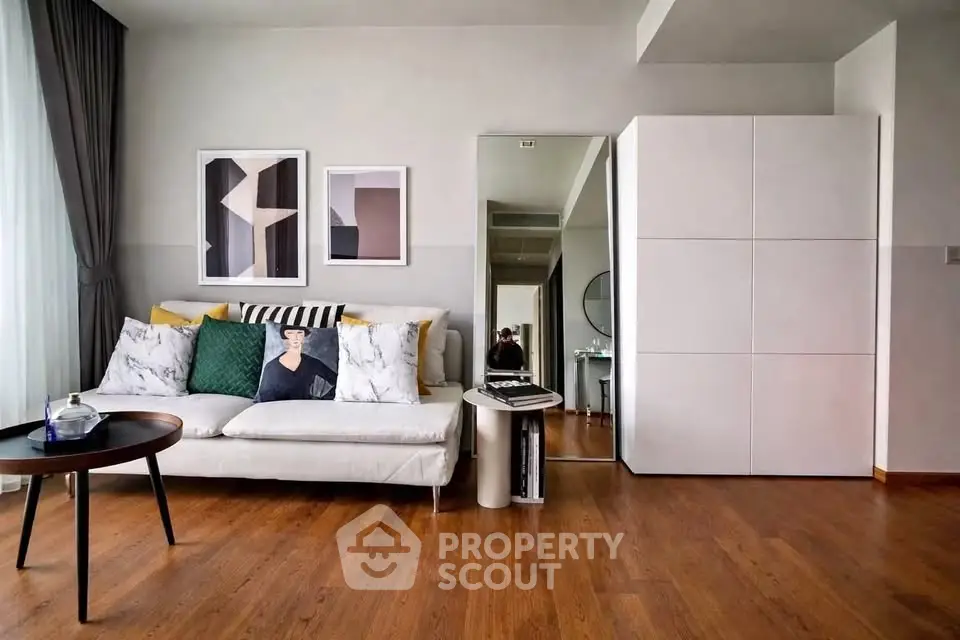 Modern living room with stylish decor and wooden flooring, featuring a cozy sofa and contemporary artwork.