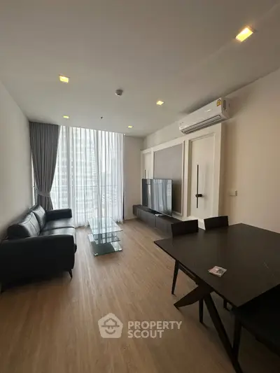Modern living room with sleek furniture and large windows in a high-rise apartment.