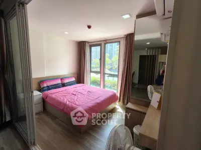 Cozy bedroom with pink bedding and large windows offering natural light.