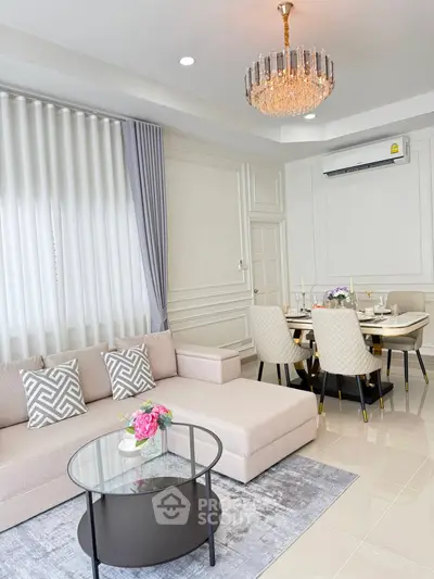 Elegant living room with modern decor and dining area, featuring a chic chandelier and stylish furniture.