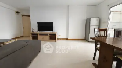 Spacious living room with modern furniture and open layout, featuring a large TV and dining area.