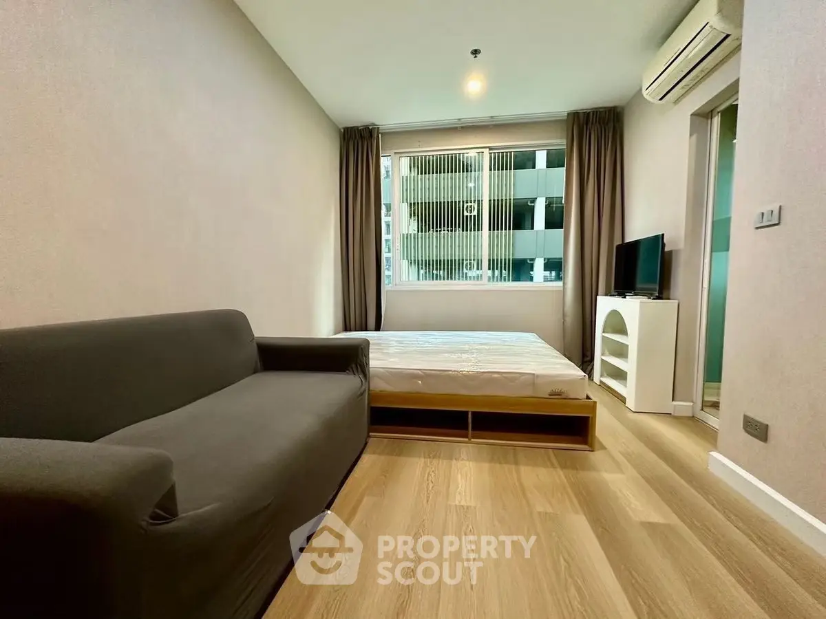 Modern bedroom with sleek design, featuring a cozy sofa and large window for natural light.