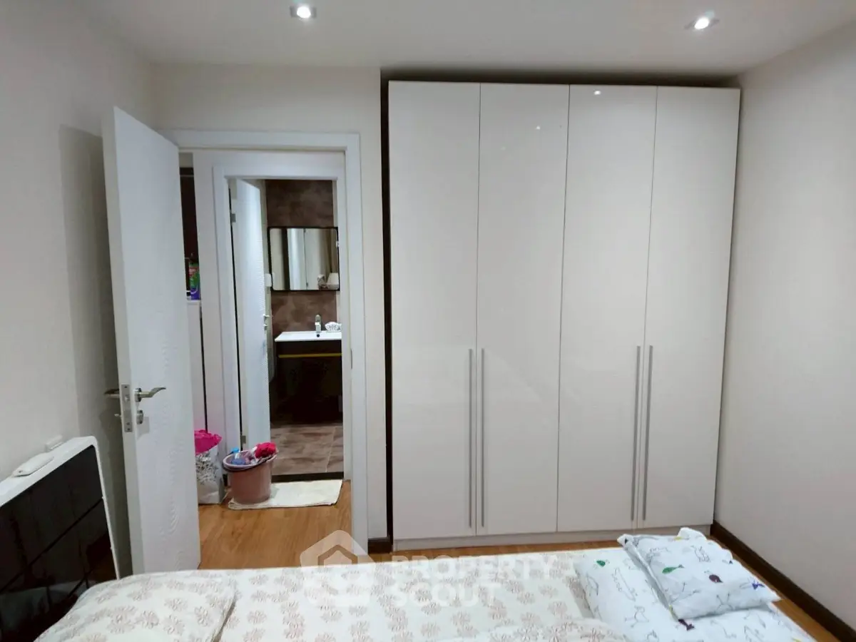 Cozy bedroom with modern wardrobe and glimpse of bathroom