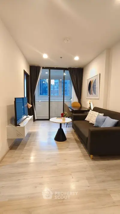 Modern living room with sleek furniture and large windows offering city views.