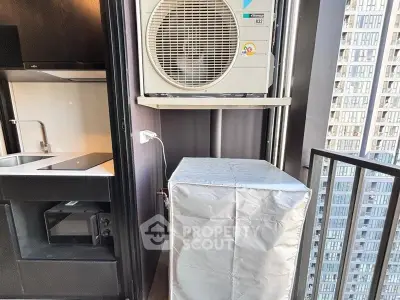 Modern apartment balcony with air conditioning unit and city view, featuring sleek kitchen area.