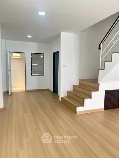 Spacious modern interior with wooden flooring and staircase, ideal for stylish living.