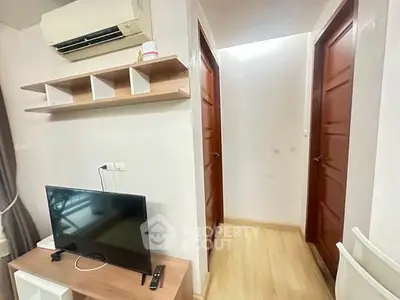 Modern apartment interior with TV, air conditioning, and wooden doors in a cozy hallway.