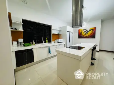 Modern kitchen with sleek white cabinetry and island, featuring open layout and contemporary art.