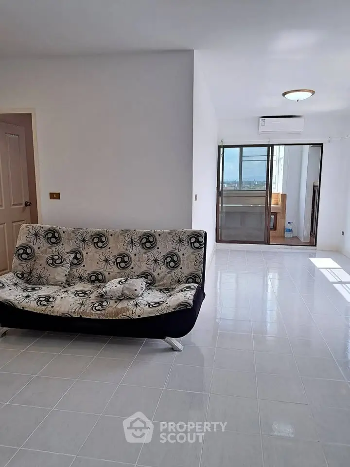 Spacious living room with modern sofa and large windows offering natural light.