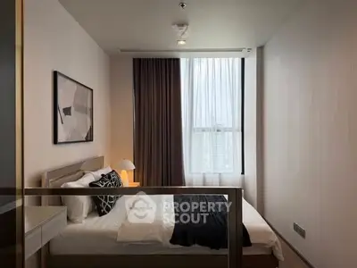 Modern bedroom with stylish decor and large window offering natural light.