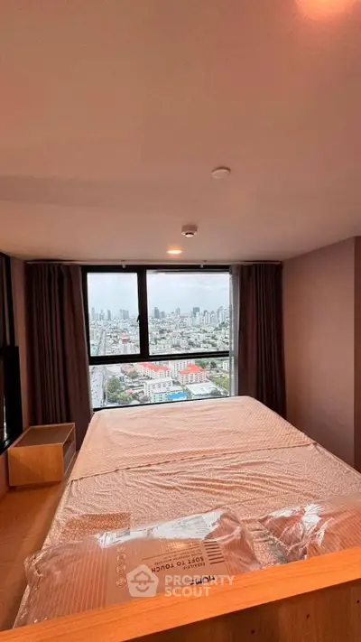 Spacious bedroom with city view, featuring large windows and modern furnishings.