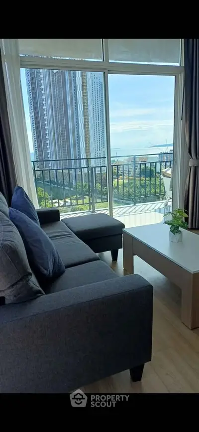 Modern living room with large windows offering stunning city view and cozy seating area.