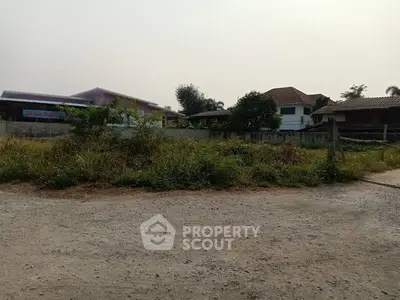 Vacant land plot in a residential neighborhood with nearby houses and greenery.