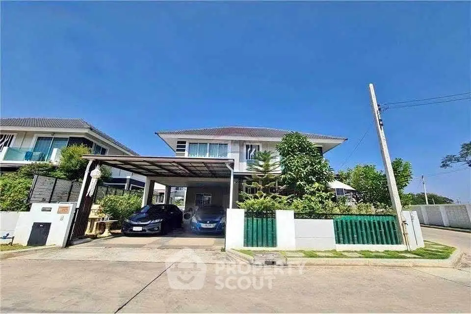Modern two-story house with carport and lush greenery in a serene neighborhood.