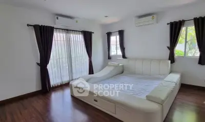 Spacious bedroom with modern white leather bed and large windows for natural light.
