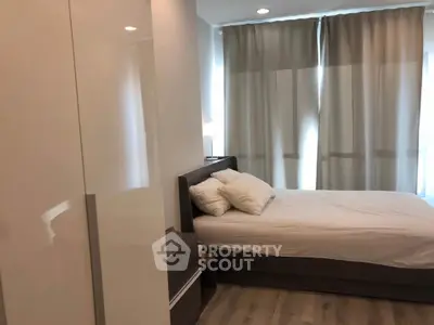 Cozy bedroom with modern furnishings and natural light through large windows.